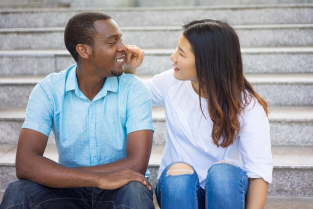 Giovane donna asiatica sorridente che flirta con l&#39;uomo afroamericano.