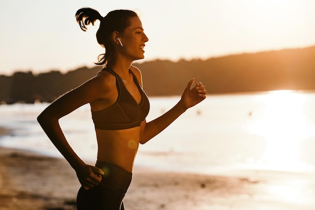 Giovane donna atletica felice che pareggia all'alba dal fiume