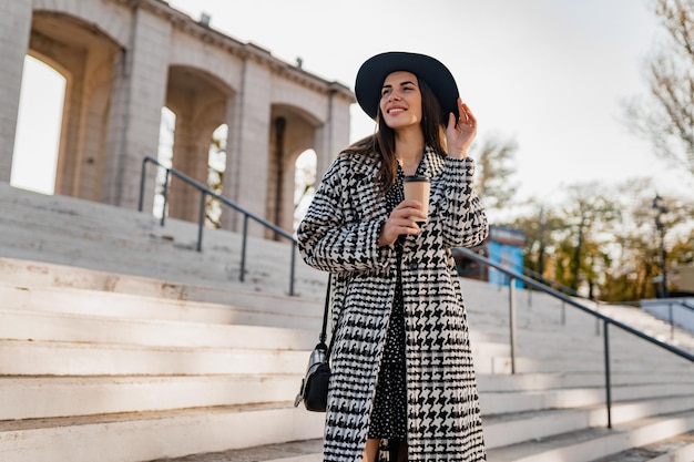 Giovane donna attraente che cammina in cappotto d'uso di autunno