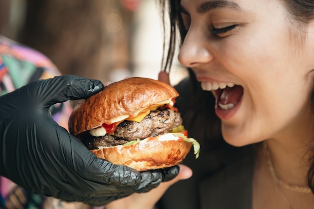 Giovane donna attraente che mangia patatine fritte e un hamburger in un ristorante