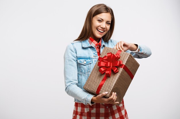 Giovane donna attraente che scopre scatola attuale che sembra felice e sorridente