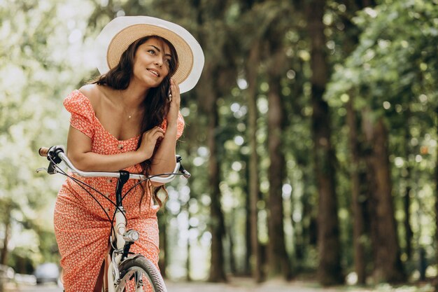 Giovane donna attraente in bicicletta da equitazione vestito e utilizzando il telefono