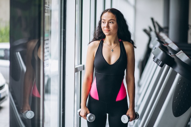 Giovane donna attraente in palestra con manubri