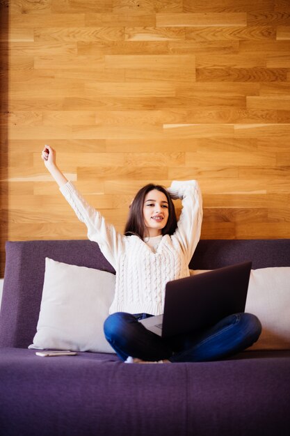 Giovane donna attraente stanca lavora a casa allungando le braccia per rilassarsi dopo una dura giornata