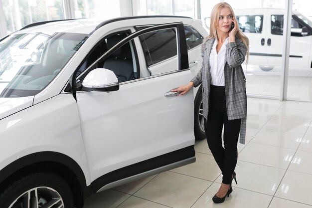 Giovane donna bionda che apre a lungo la porta di automobile