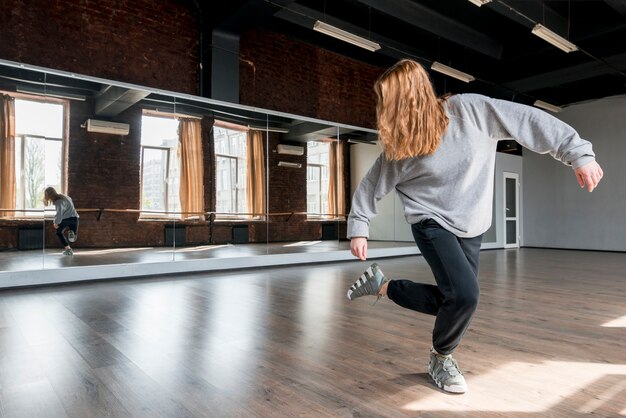 Giovane donna bionda che balla contro lo specchio nello studio di ballo