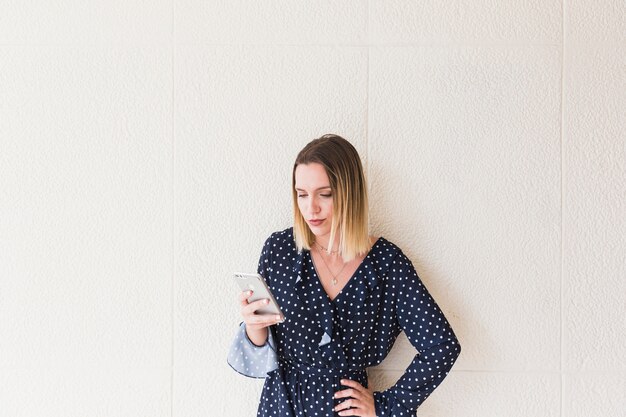 Giovane donna bionda che per mezzo del telefono cellulare