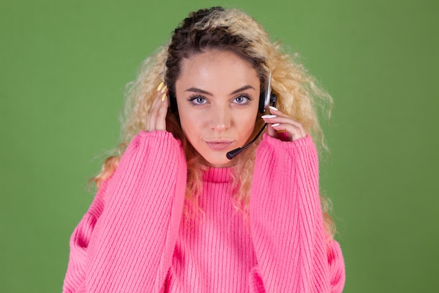 Giovane donna bionda con capelli ricci lunghi in maglione rosa su green