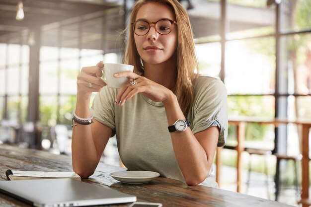 Giovane donna bionda con gli occhiali nella caffetteria
