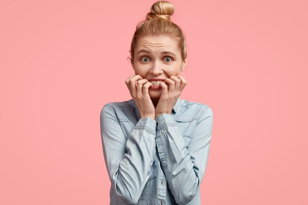 Giovane donna bionda con i capelli in chignon e indossa una giacca di jeans