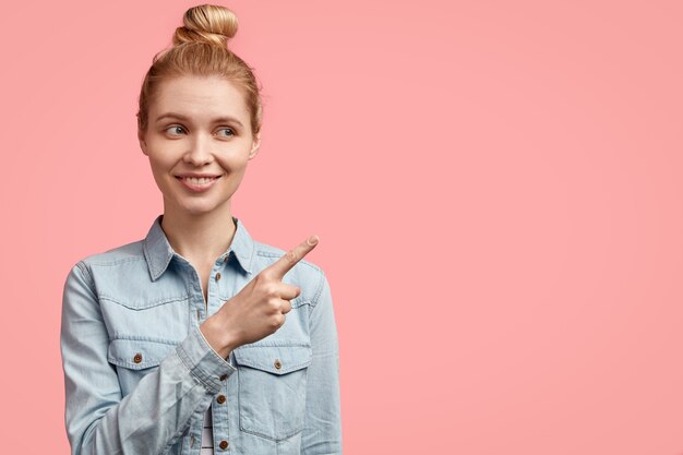 Giovane donna bionda con i capelli in chignon e indossa una giacca di jeans