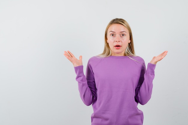 Giovane donna bionda con un maglione viola