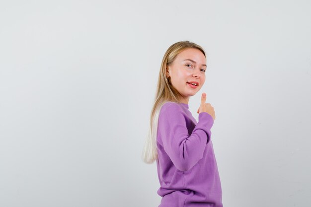 Giovane donna bionda con un maglione viola