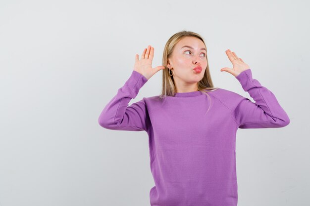 Giovane donna bionda con un maglione viola