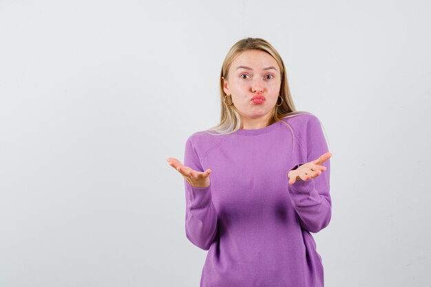 Giovane donna bionda con un maglione viola