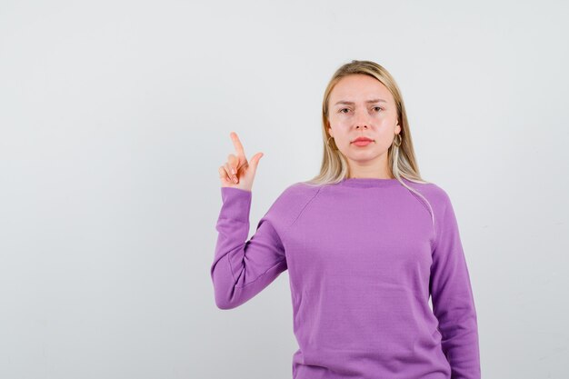 Giovane donna bionda con un maglione viola