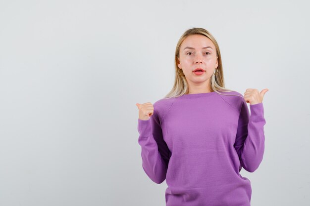 Giovane donna bionda con un maglione viola