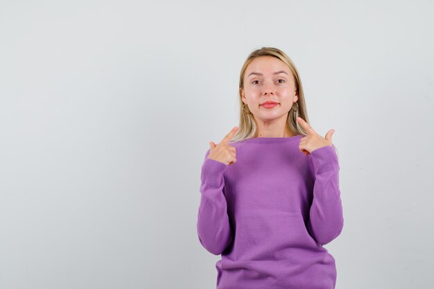 Giovane donna bionda con un maglione viola