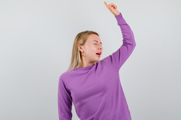 Giovane donna bionda con un maglione viola