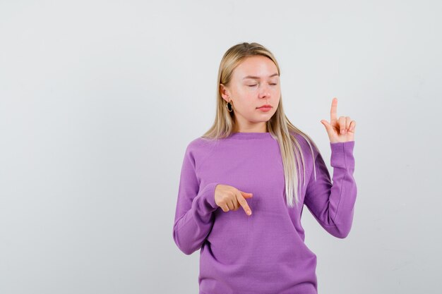 Giovane donna bionda con un maglione viola