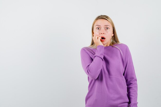 Giovane donna bionda con un maglione viola