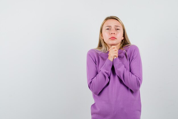 Giovane donna bionda con un maglione viola