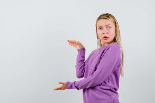 Giovane donna bionda con un maglione viola