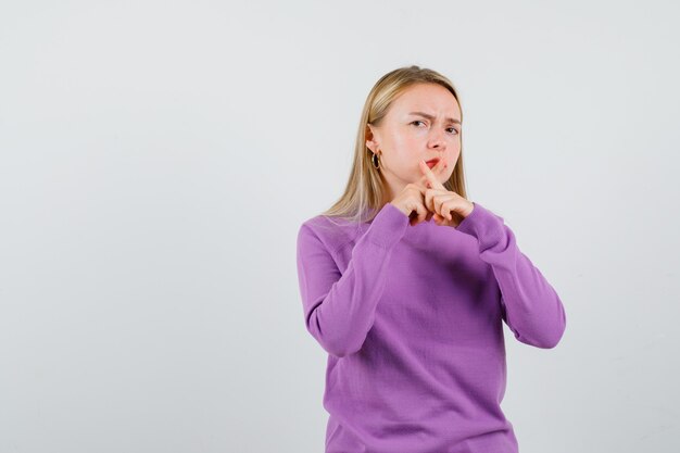 Giovane donna bionda con un maglione viola