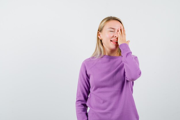 Giovane donna bionda con un maglione viola