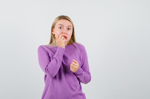 Giovane donna bionda con un maglione viola