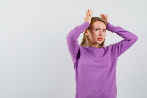 Giovane donna bionda con un maglione viola