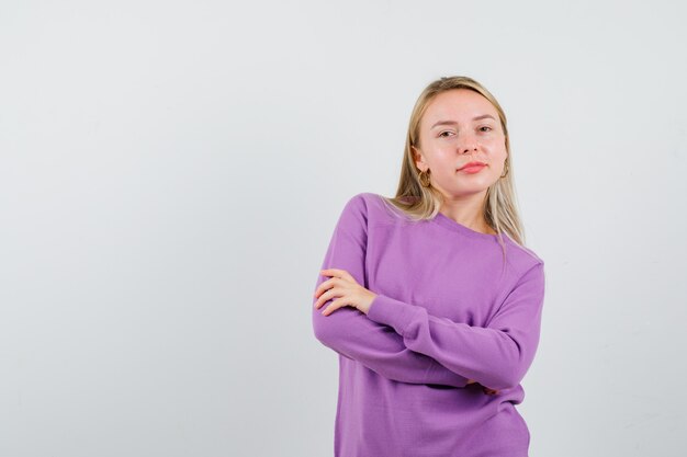 Giovane donna bionda con un maglione viola