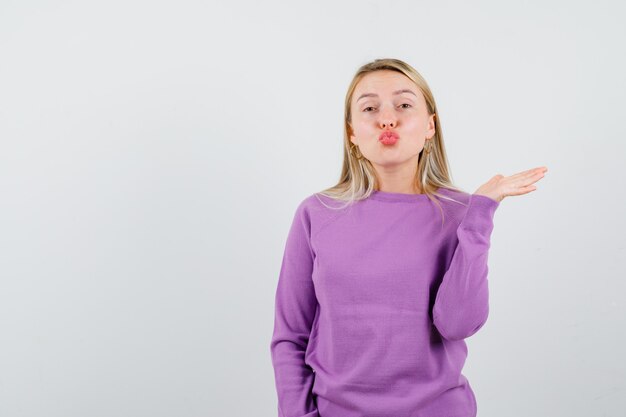 Giovane donna bionda con un maglione viola