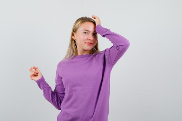 Giovane donna bionda con un maglione viola