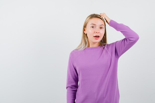 Giovane donna bionda con un maglione viola