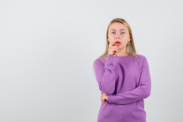 Giovane donna bionda con un maglione viola