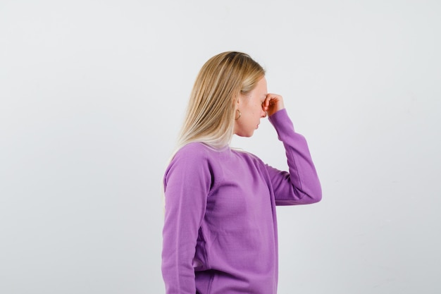 Giovane donna bionda con un maglione viola