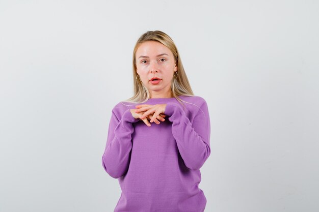 Giovane donna bionda con un maglione viola