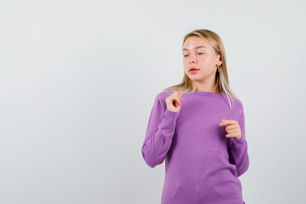 Giovane donna bionda con un maglione viola