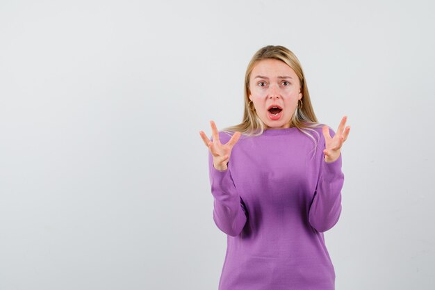 Giovane donna bionda con un maglione viola