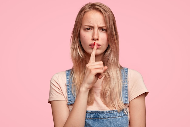 Giovane donna bionda con una tuta in denim