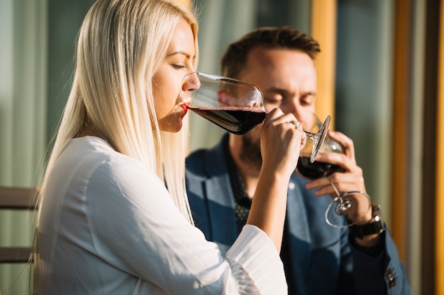 Giovane donna bionda e il suo fidanzato bere bicchiere di vino rosso