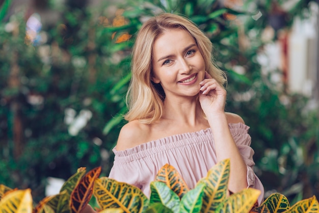 Giovane donna bionda felice che sta nel giardino