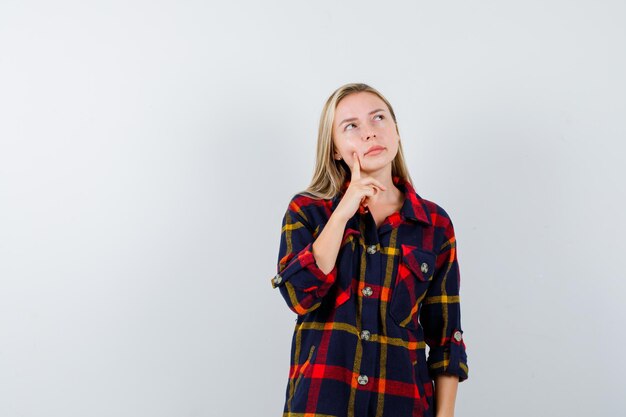 Giovane donna bionda in una camicia a scacchi pensando