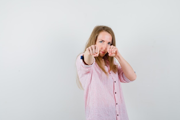 Giovane donna bionda in una camicia rosa casual pronta a combattere