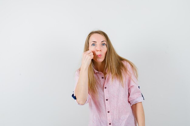 Giovane donna bionda in una camicia rosa casual