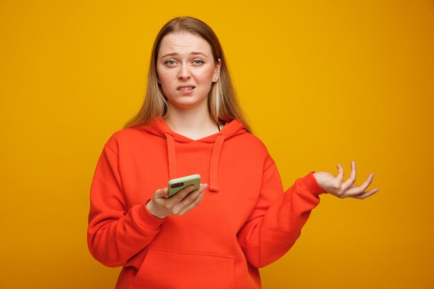 Giovane donna bionda senza tracce che tiene il telefono cellulare che mostra la mano vuota