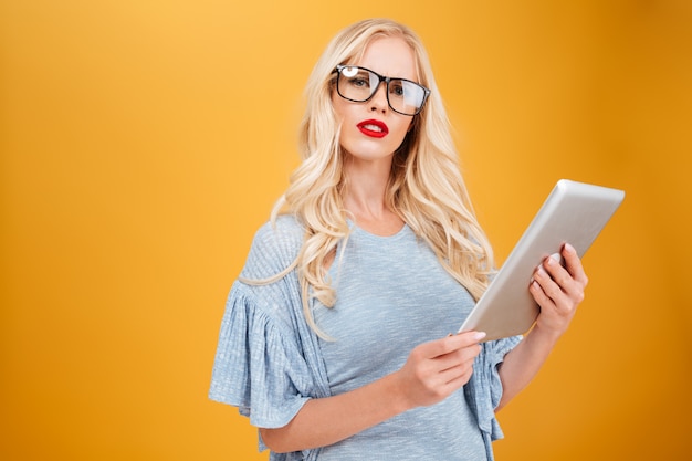 Giovane donna bionda seria che per mezzo del computer della compressa.