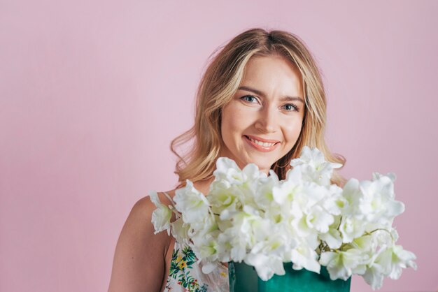 Giovane donna bionda sorridente che tiene il mazzo del fiore bianco