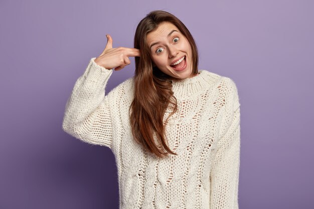 Giovane donna bruna che indossa un maglione bianco